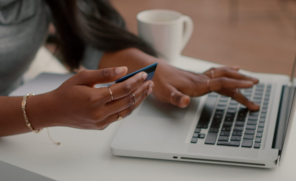 Home black student holding cred card in hands doing electronic transcation searching online store